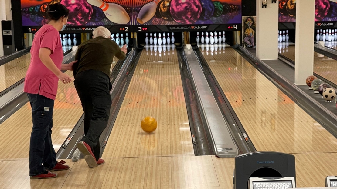 Deltagare i Rydbogårdens dagliga verksamhet spelar bowling. Personal hjälper till.