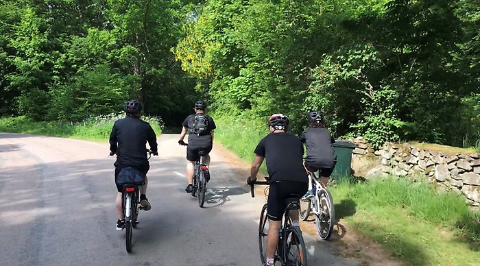 Cyklister som cyklar på väg på väg in på en grusväg i grön skog